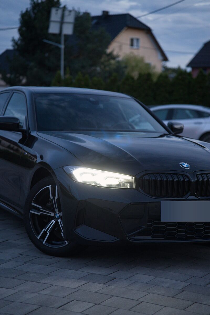 Pionowe ujęcie ciemnego sedana BMW z przodu