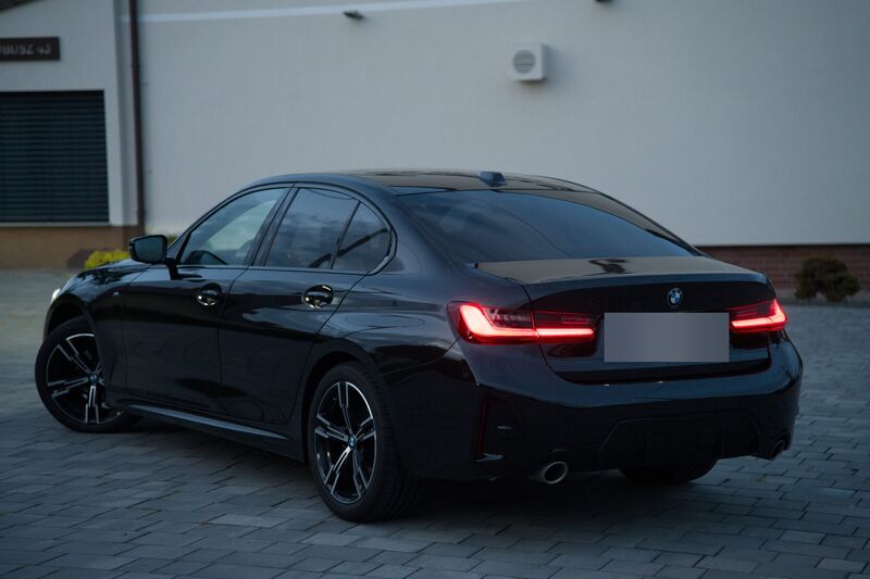 Ciemny sedan BMW widziany z tyłu od lewej strony