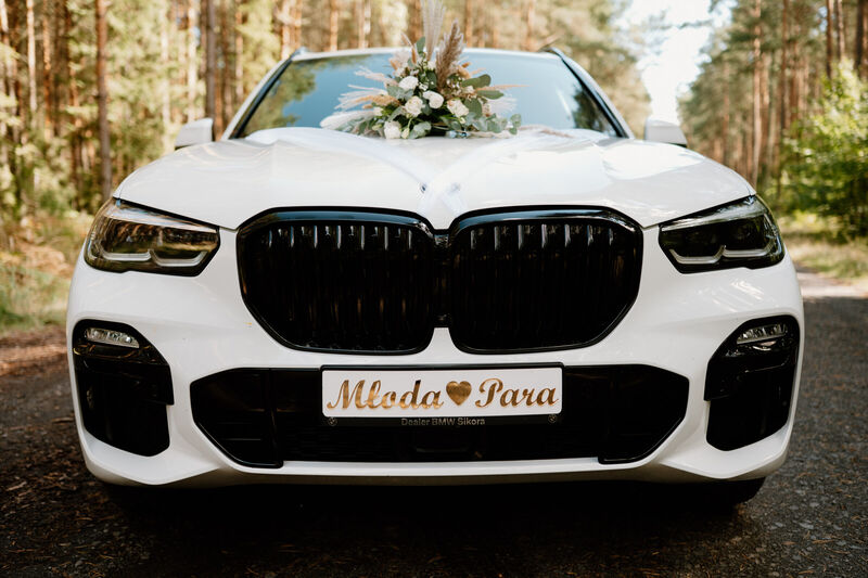 Białe BMW X5 do ślubu z tablicą Młoda Para, widok z przodu