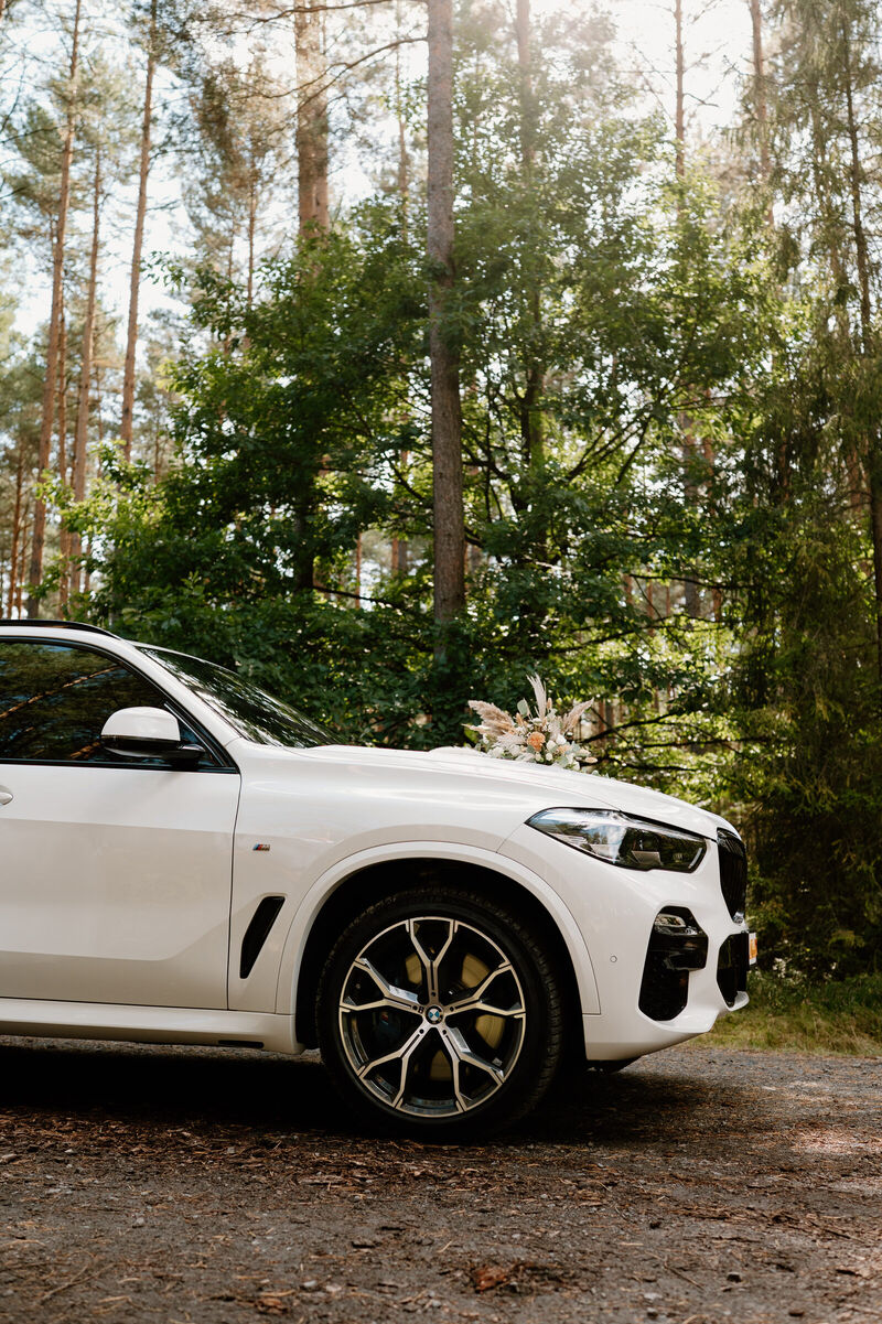 Białe BMW X5 z dekoracją ślubną na masce